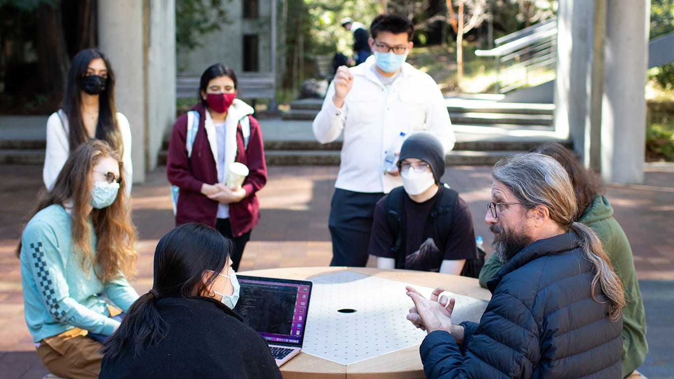 Students discussing a topic outside with their professor