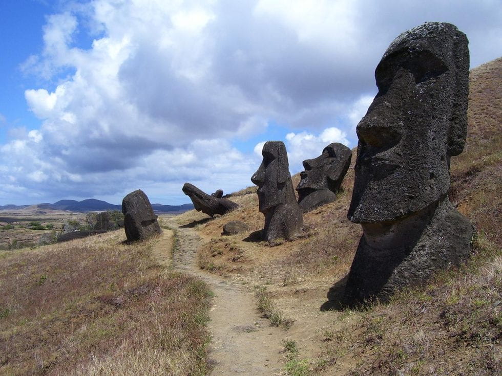 Five giant stone heads characteristic to Rapa Nui standing in a row with blue sky in the background