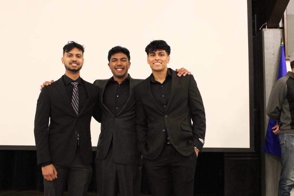 Three male students in black suits.
