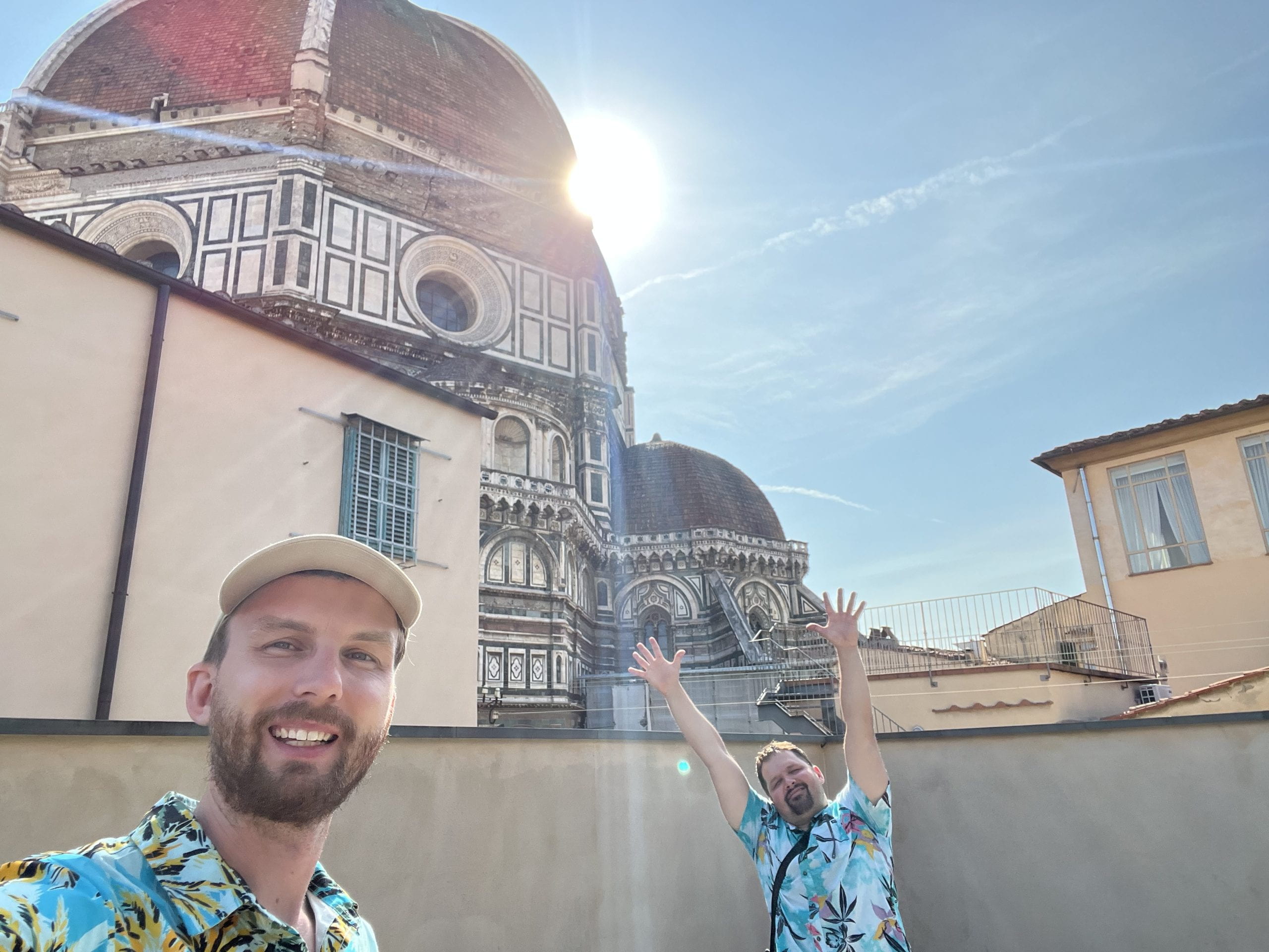Two men in blue Hawaiin print shirt in front of an elaborate, domed church roof.